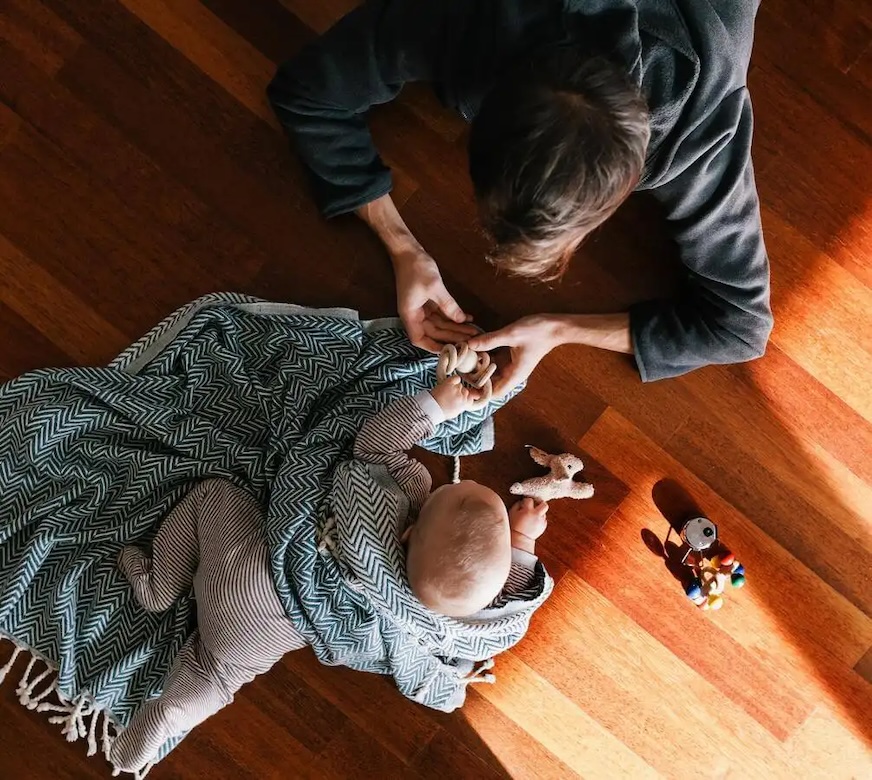 Man playing with baby on hardwood floor